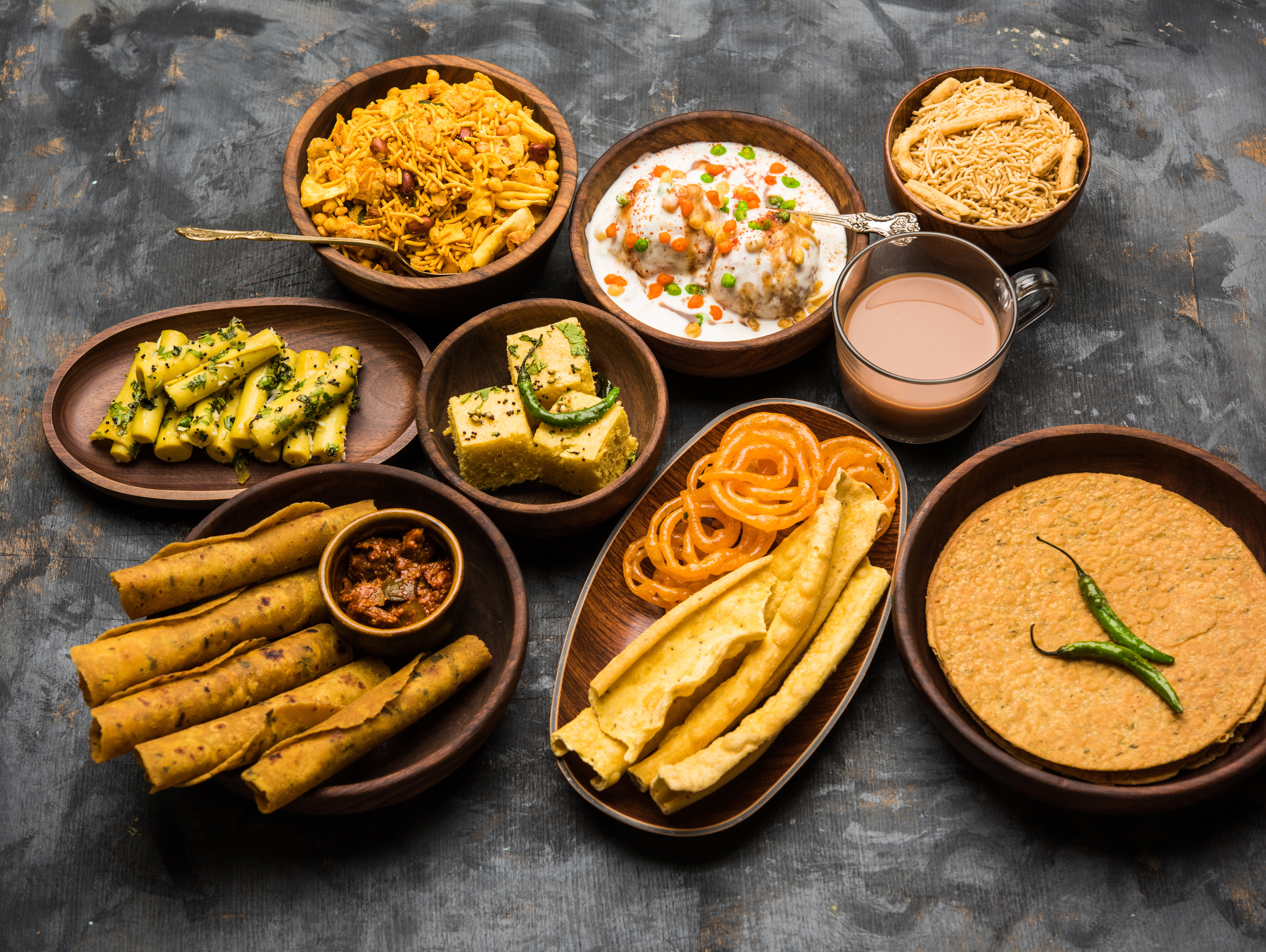 Group of Gujarati snacks like jalebi-fafda, thepla, khaman dhokla, aloo bhujiya, khandvi,khakra, dahi vada, gathiya with hot tea